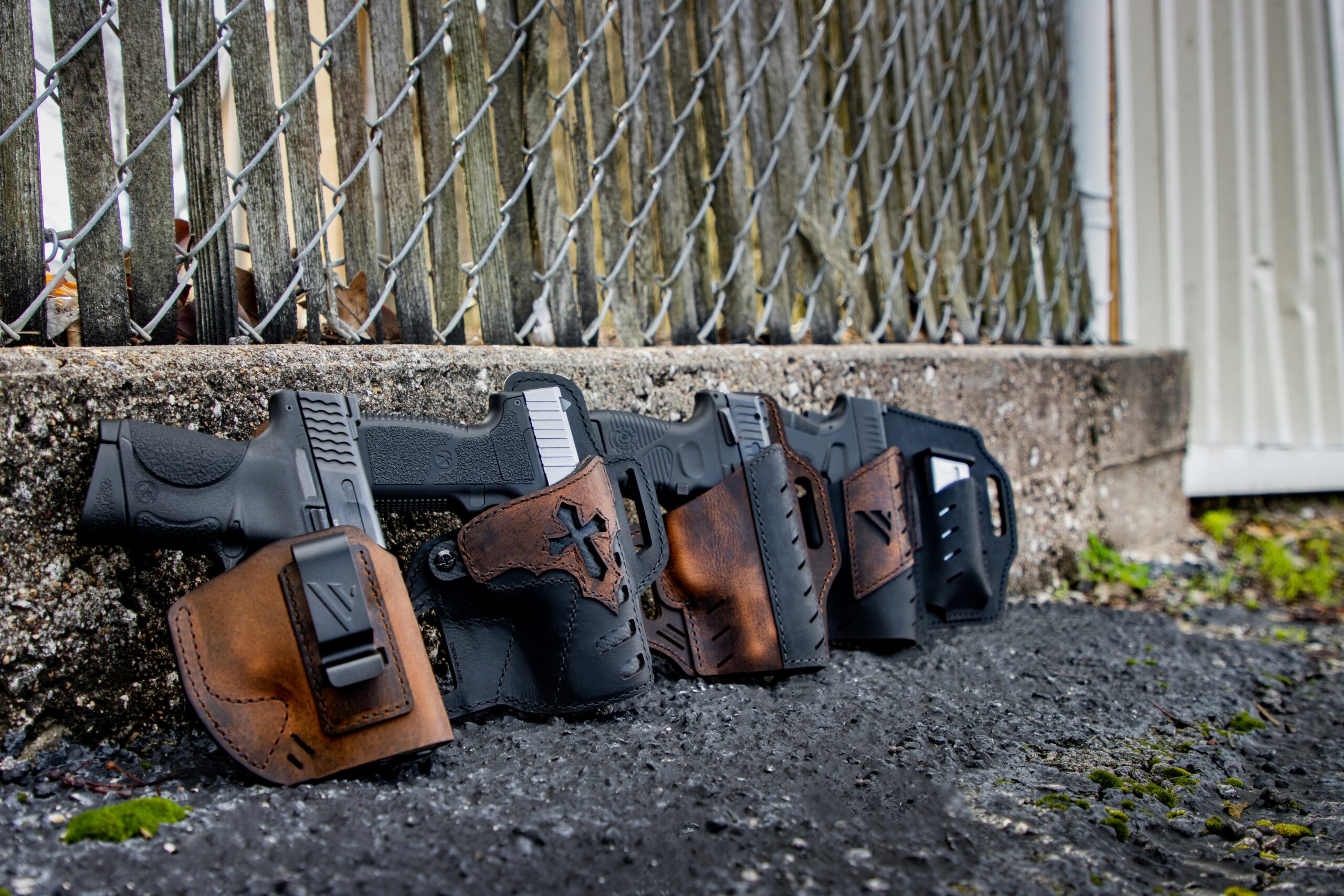 a row of holsters on the ground behind a chain link fence