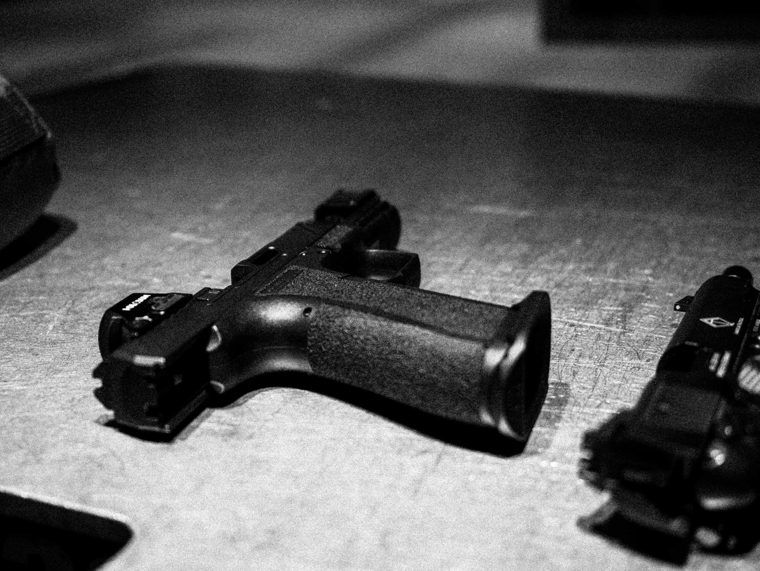 Pistols are seen resting on a tabletop surface.